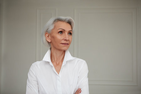 Close up portrait of beautiful older woman standing by wallの写真素材