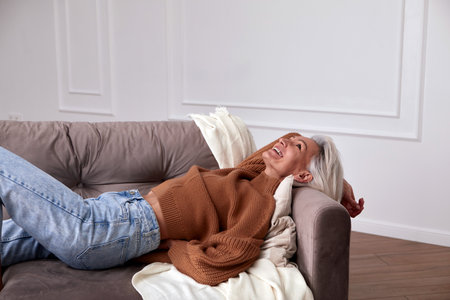 Positive middle aged woman laughing on couchの写真素材