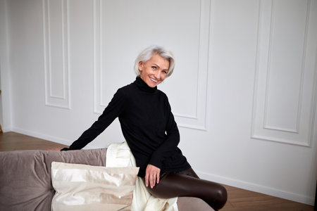 Stylish mature woman on sofa in living roomの写真素材