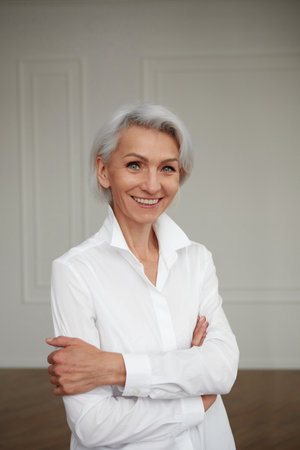 Close up portrait of beautiful older woman standing by wallの写真素材