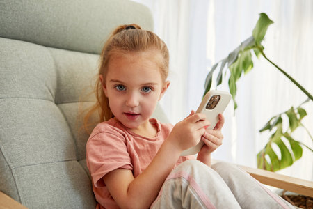 Little girl with smartphone looking at camera