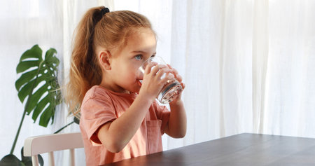 Cute child is drinking a cup of waterの写真素材