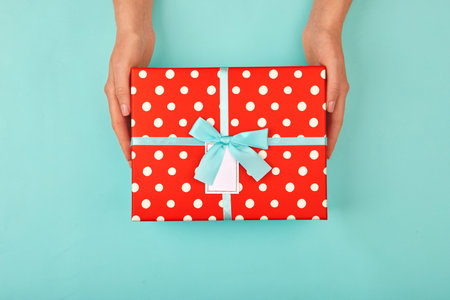 Hands holding gift box turquoise blue backgroundの写真素材