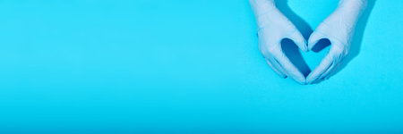 Doctors hands in medical gloves in shape heart blue backgroundの写真素材