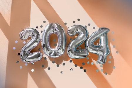 Silver numbers 2024 new year balloons in sunlight Peach Fuzz backgroundの写真素材
