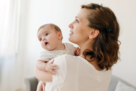 Happy mother carrying adorable baby at homeの写真素材