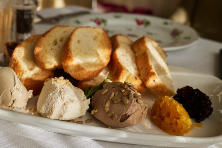 Fried toast bread on plates with assorted pates on the kitchen table in the sunの写真素材