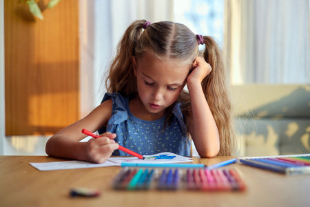 Concentrated girl painting with colorful pencilsの写真素材