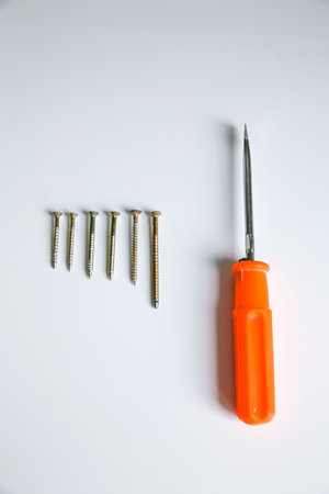 screws evenly stacked on a white background and orange screwdriverの写真素材