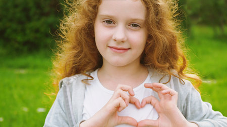 Little girl folded her hands a heart shaped.の写真素材