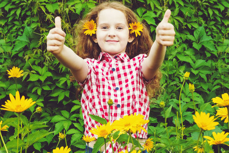 Little girl with daisy in her hair in summer park.の写真素材