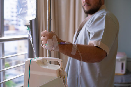 Close-up. patient with a dropper looks out the window of the hospital room and smiles. back view. Healthcare concept.の写真素材