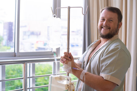 patient with a dropper looks out the window of the hospital room and smiles. Healthcare conceptの写真素材
