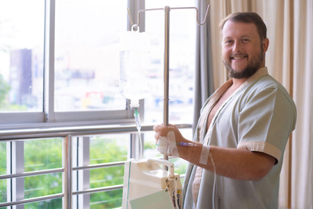patient with a dropper looks out the window of the hospital room and smiles. Healthcare conceptの写真素材