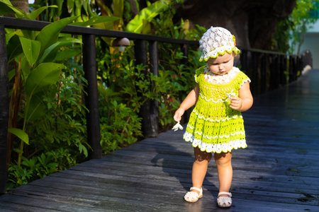 little girl in a knitted dress, chamomile, looks at the green leaves, the concept of children fashion. the child is surprisedの写真素材