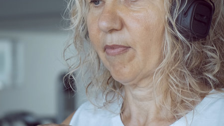 senior woman on the treadmill in the gym listening to music with headphones, close-up.の写真素材