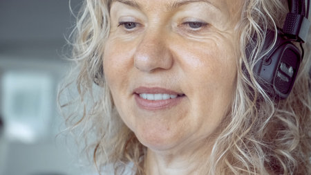 senior woman on the treadmill in the gym listening to music with headphones, close-up.の写真素材