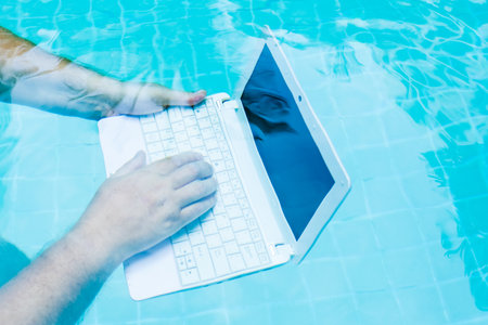 Male works on minicomputer under water. Minicomputer at the bottom of the pool. The concept of a lot of work at work. Blur abstract background.の写真素材