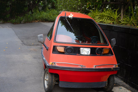 Inplatnet red three-wheeled light car on the street of Pattaya Thailand.