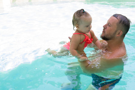 happy father swims in the pool with his daughterの写真素材