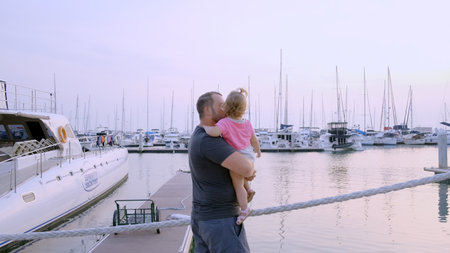 Pattaya, Thailand - May 10, 2019: Dad with a little daughter in his arms go to the marina of the yacht parking, slow motion, 4k.の写真素材
