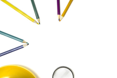 colored pencils lie in a half circle , on and magnifier isolated white background. Copy space.の写真素材