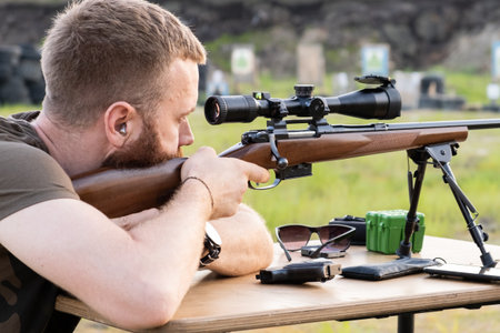 A man with glasses with a beard holds a sniper rifleの写真素材