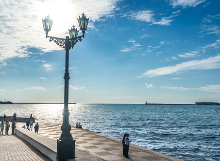 RUSSIA, Sevastopol-JUNE 29, 2015: Lantern on the Embankment in Sevastopol. People stand and look at the bay.のeditorial素材