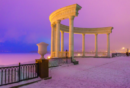 Rotunda on the embankment and a beautiful view of the frozen Izhevsky pond in the winter, in the evening, before sunset. Russia.の写真素材