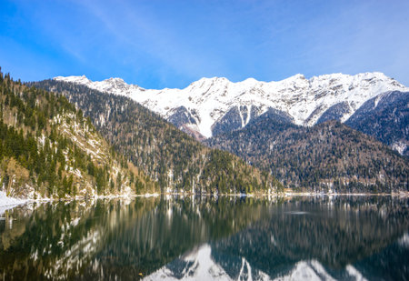 Beautiful mountain lake in the spring. In the background, mountains covered with snow are reflected in the waters of the lake.の写真素材
