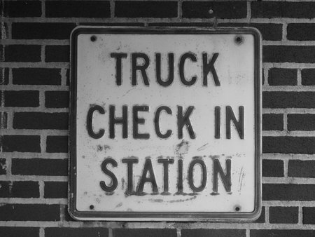 Monochromatic image of an iron plate with the text truck check in station engraved in it.の写真素材