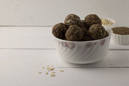 Oat, seed and nut energy balls in white bowl on a white table