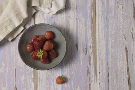 Gray plate of ripe, fresh strawberries on a pink rustic backgroundの写真素材