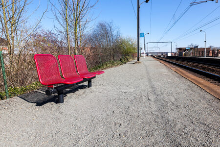 near the rail in railway station is an sitting bench