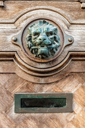 on an old door is there an lion head doorknob whit an mailboxの写真素材