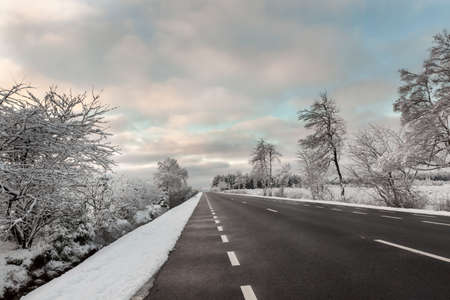Frozen trees and snowy land road at winterの写真素材