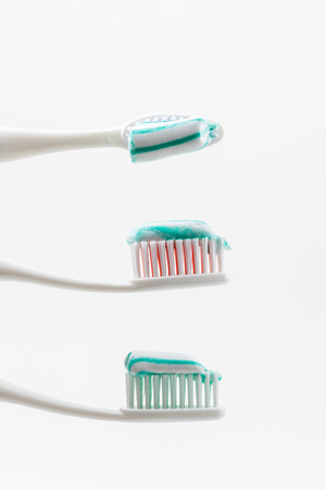 two toothbrushs with toothpaste with green and white colors between themの写真素材