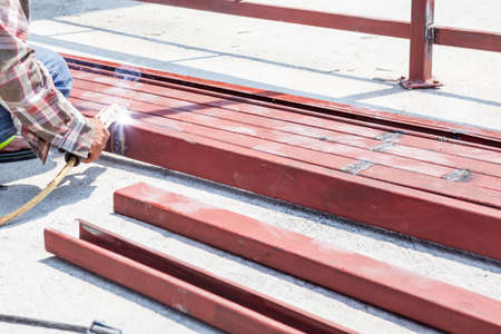 an man welding the iron bars together