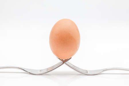 egg on two semetriche forks with a white backgroundの写真素材