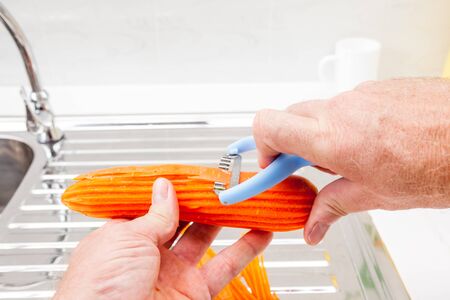 in the kitchen, I peel a carrot into pieces to be cut with a serrated knifeの写真素材