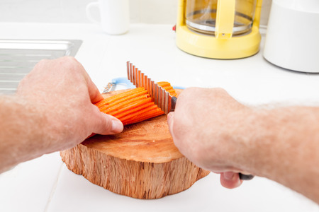 in the kitchen, I peel a carrot into pieces to be cut with a serrated knifeの写真素材