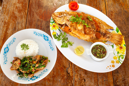 Thai fried fish and cooked on a plate with lemon and the peel of an tomato