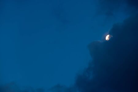 early in the morning on a cloudy day is the moon behind the blue cloud