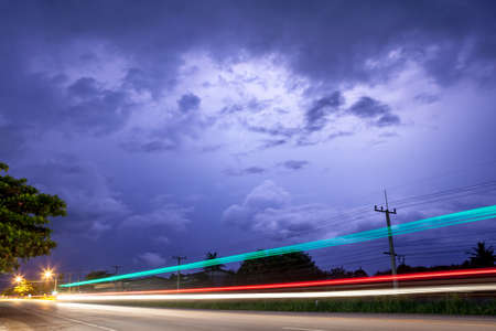 dark cloudy with lightning and light rays in the foreground of the road,