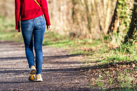 an young woman with an jeans trousers walk in the park