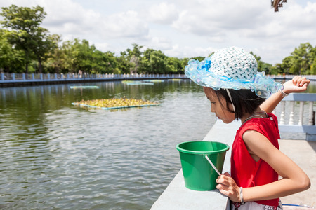 at the temple of Buddha there is a large pond with many fish of which the girl was feedingの写真素材