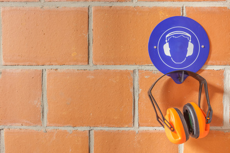 an blue placard for compulsory wearing of ear protection and a hearing protector on the hookの写真素材