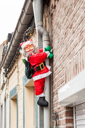 along the drainpipe next to the house Santa Claus climbs upの写真素材