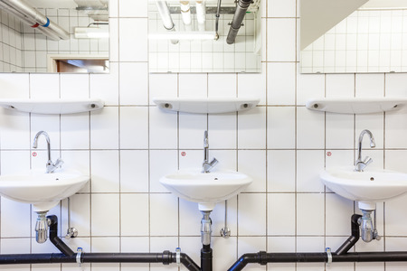 in an public restroom hangs on an wall of an white sinkの写真素材