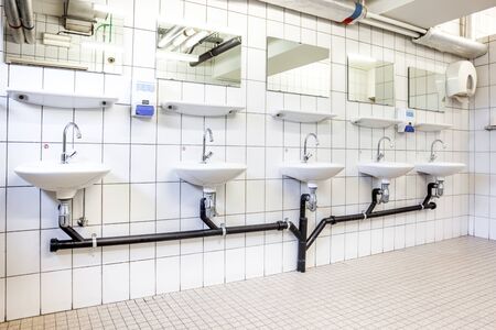 in an public restroom hangs on an wall of an white sink
